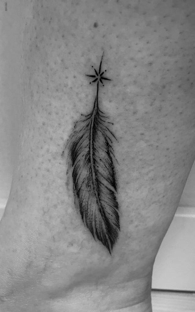 Fein schattierte Feder mit kleinem Stern als Tattoo am Knöchel.